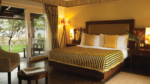 double bed and chair in a room at The Serai Kabini-13