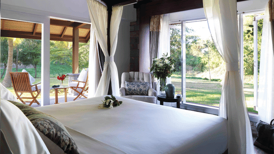 A king size bed in the residence room with floor to ceiling windows at The Serai, Kabini.