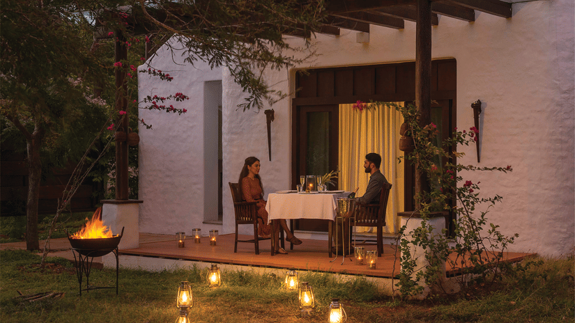 A couple having a romantic dinner in Bandipur with lights next to them at The Serai Bandipur.