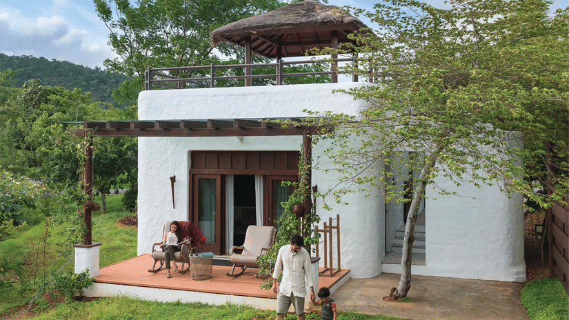 Luxury white eco-resort villa with rooftop patio and surrounding green landscape.