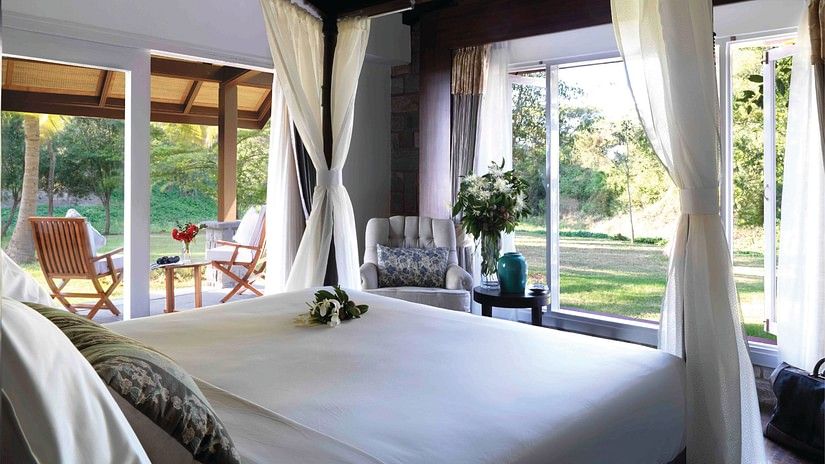 a double bed in The residence room with floor to ceiling windows at The Serai, Kabini