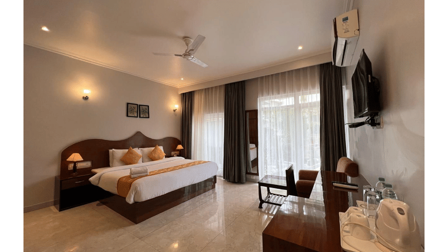 A well-lit guest room with a double bed, desk, and television at A S Hotels, Khajuraho.