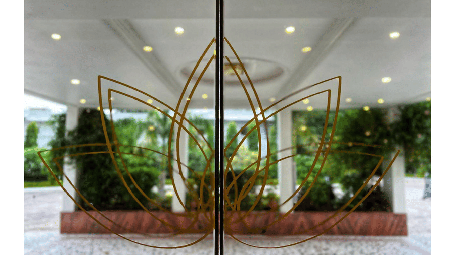 A glass entrance with a metallic lotus-shaped design at A S Hotels, Khajuraho.