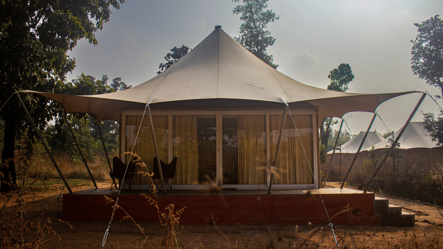 Exterior view of a circular luxury safari tent built on a raised brick platform - Umaria Safari Camp