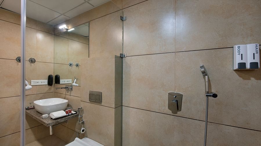 A modern hotel bathroom featuring a shower cubicle and basic amenities - SK Lords Inn Ahmedabad