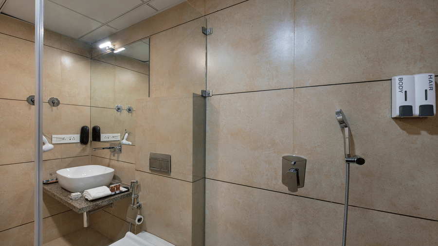A modern hotel bathroom featuring a shower cubicle and basic amenities - SK Lords Inn Ahmedabad