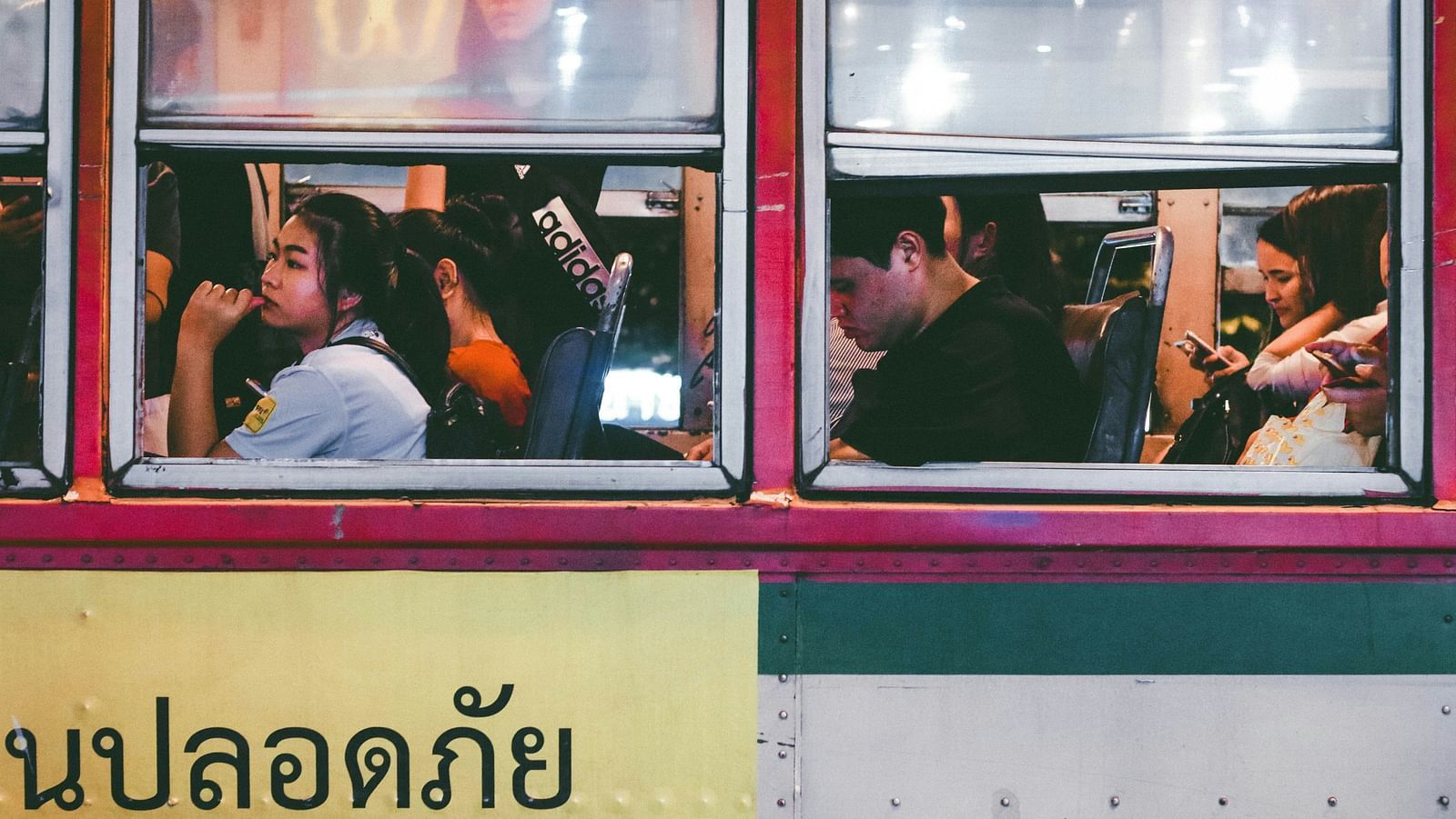 A close up of a bus with many people inside it sitting and standing while commuting.
