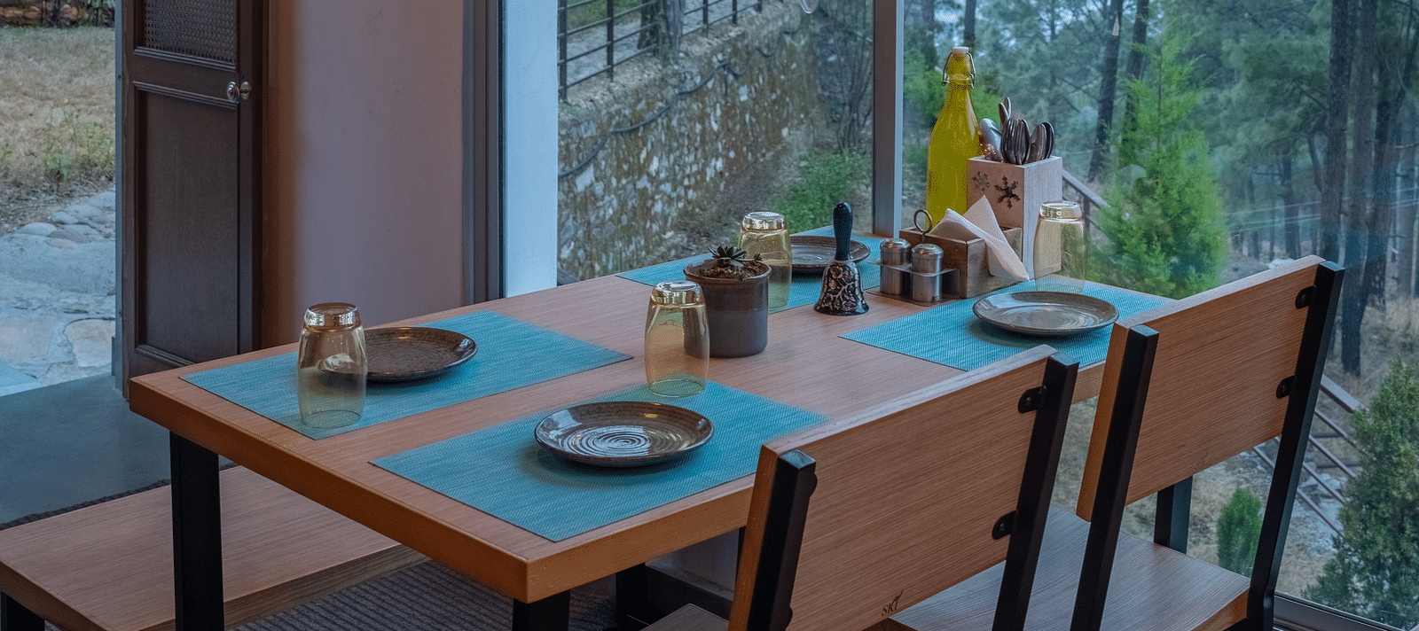 A restaurant with a large glass window beside it, offering a view of the interior dining area at BluSalzz Escapade Resort, Lansdowne