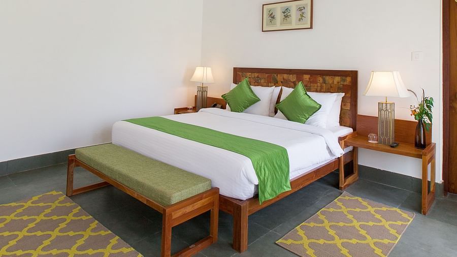 A room at Saraca Resort & Spa Corbett with a double bed, side tables and a chandelier hanging from the ceiling