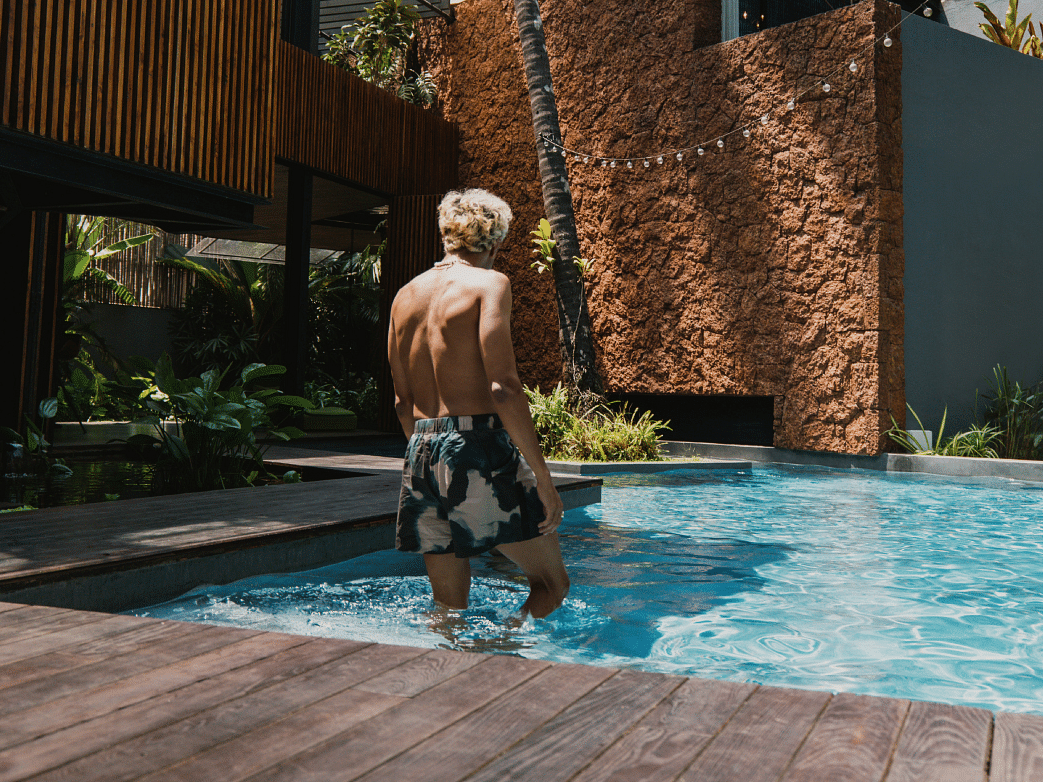 Man enjoying a refreshing dip in a private pool at a luxury tropical retreat