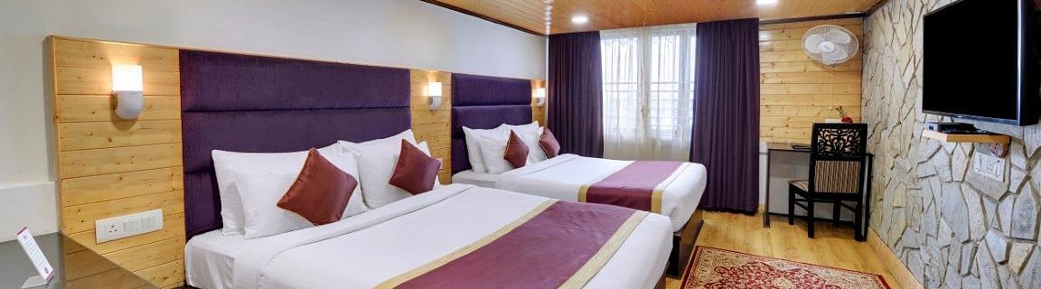 An image of a room with twin bed, flat screen TV, decorative lighting - Sumitel Darjeeling