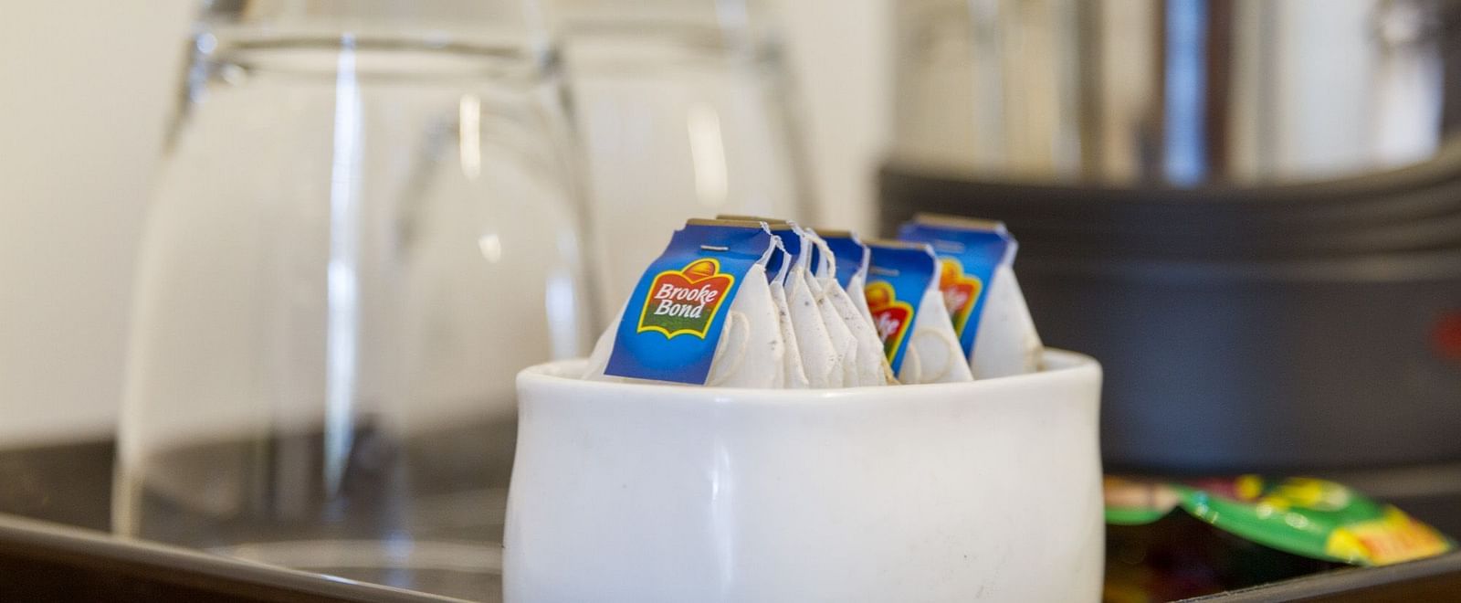 A tray presenting drinking glasses and sachets of tea and coffee at Sanctum Suites Whitefield, Bangalore.