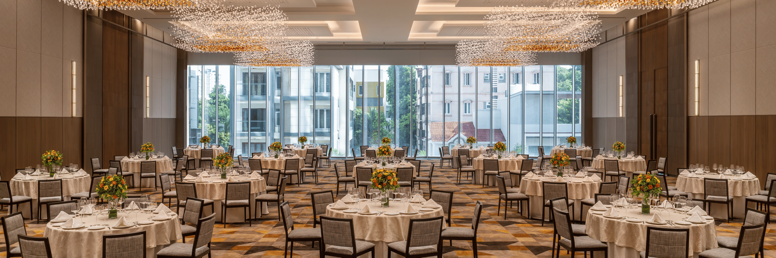 The spacious Ballroom 1 set with round banquet tables, modern chandelier lighting, and large windows at The Residency Towers Chennai.