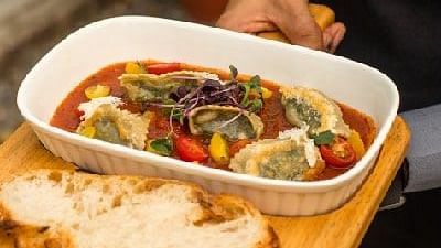 Staff member at Karma Chalets holding a wooden tray with a dish of stir-fried vegetables and two slices of bread.