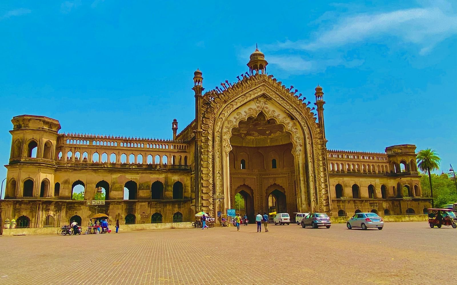A far out view of Rumi Darwaza with people walking in front of it.