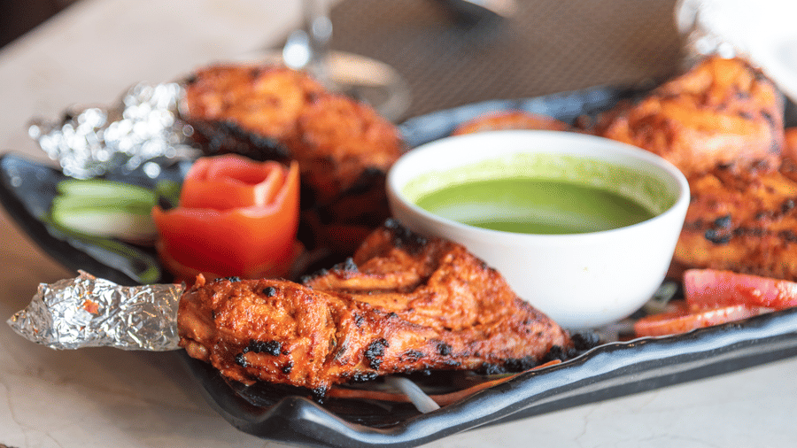 A tempting platter of grilled chicken served with fresh vegetables, and green chutney beautifully presented for diners at The Solitaire Resort.