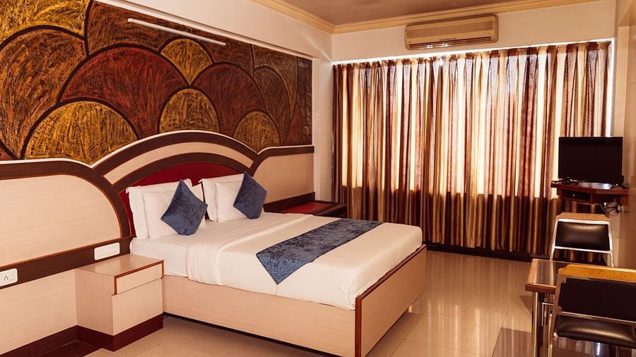 full view image of the executive room at the grand krishna room in bengaluru featuring a double bed and shiny curtains at the far end of the room
