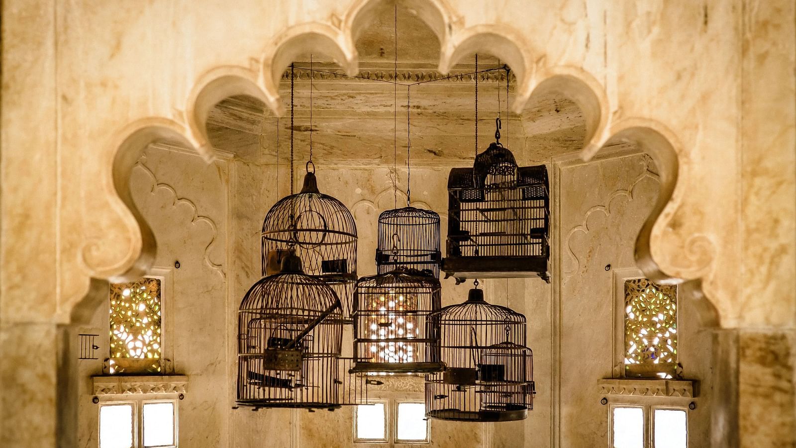 Bird cages inside a royal building with stone carvings.