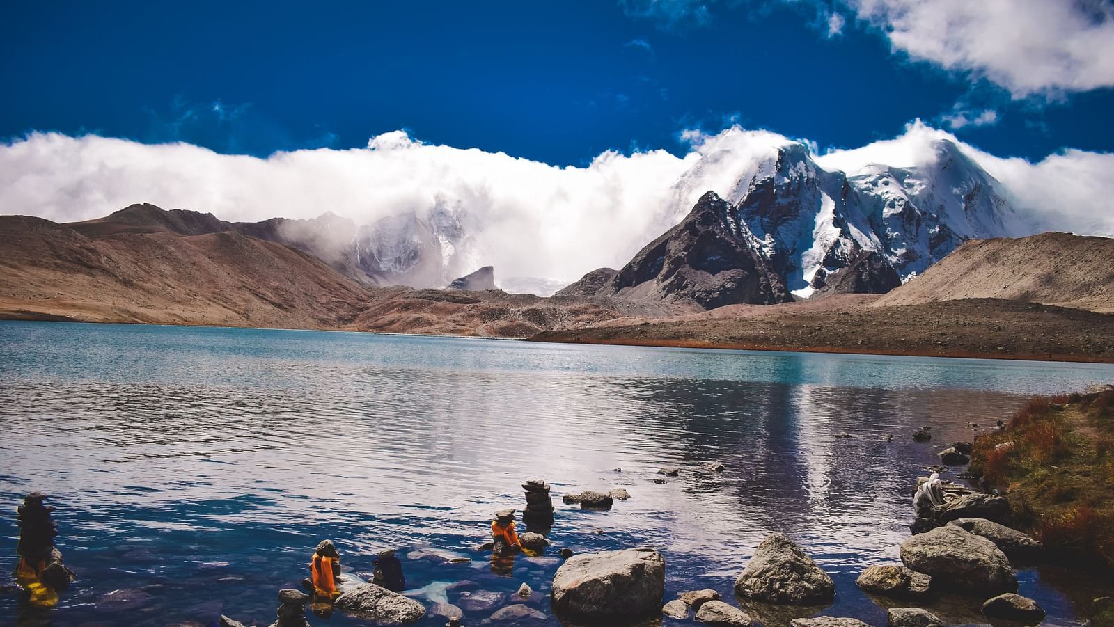 An image of a lake with the backdrop of mountains and blue sky
