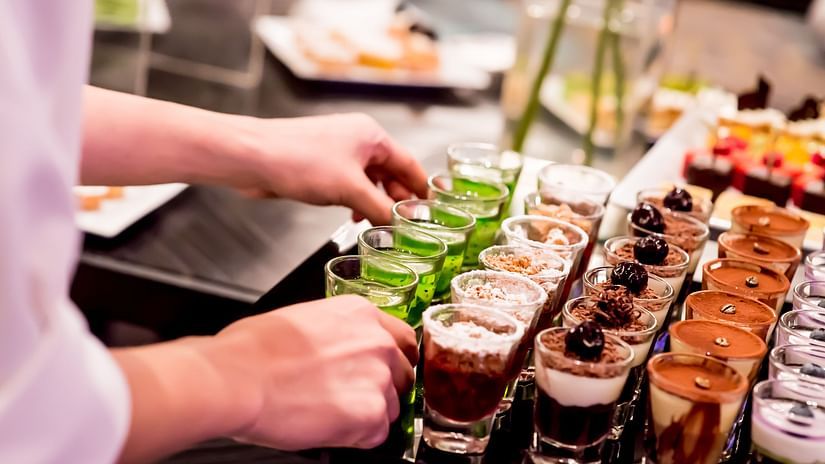 a person keeping ice creams in a shot glass during a buffet - La Maison Hotel, Doha