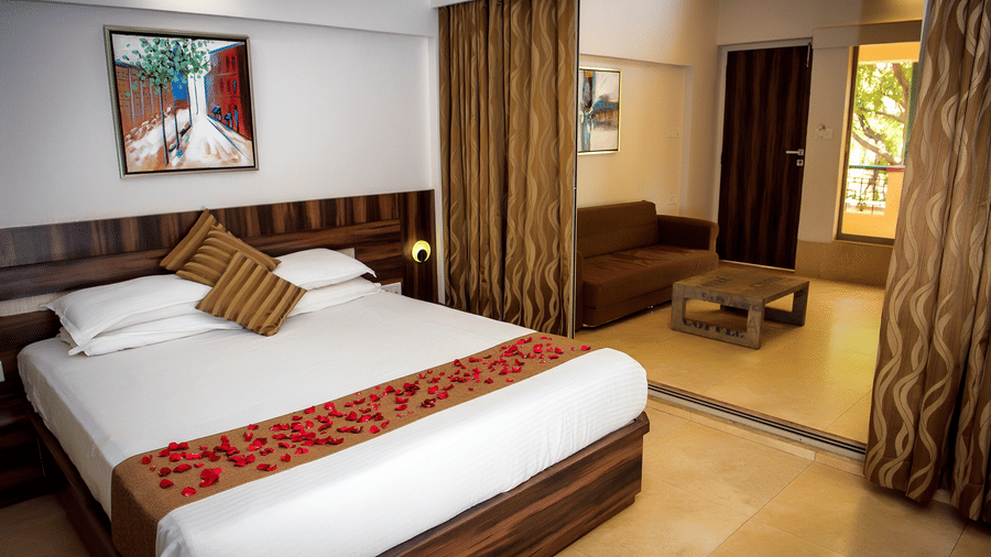 Deluxe villa bedroom interior featuring a bed, sofa and coffee table - Adamo Resort Matheran.
