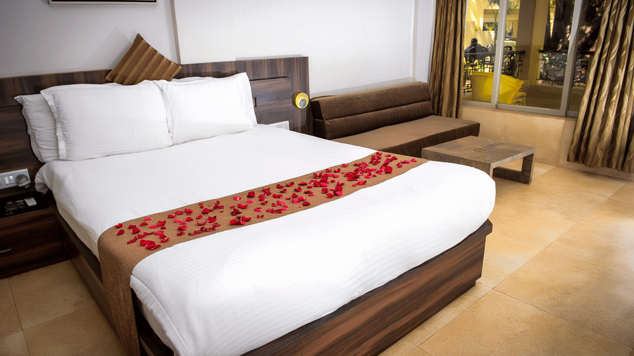 A close up view of the bed in Regent Room with its sofa and glass doors that lead to the balcony.