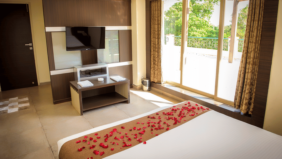 The bedroom of the Royal Suite with bed, TV, console and glass doors leading to the balcony.