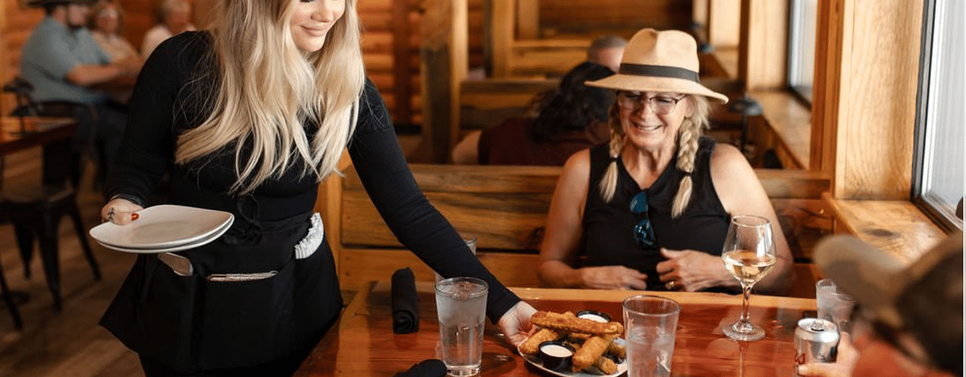 A waitress serving a lady in a restaurant with a warm ambience