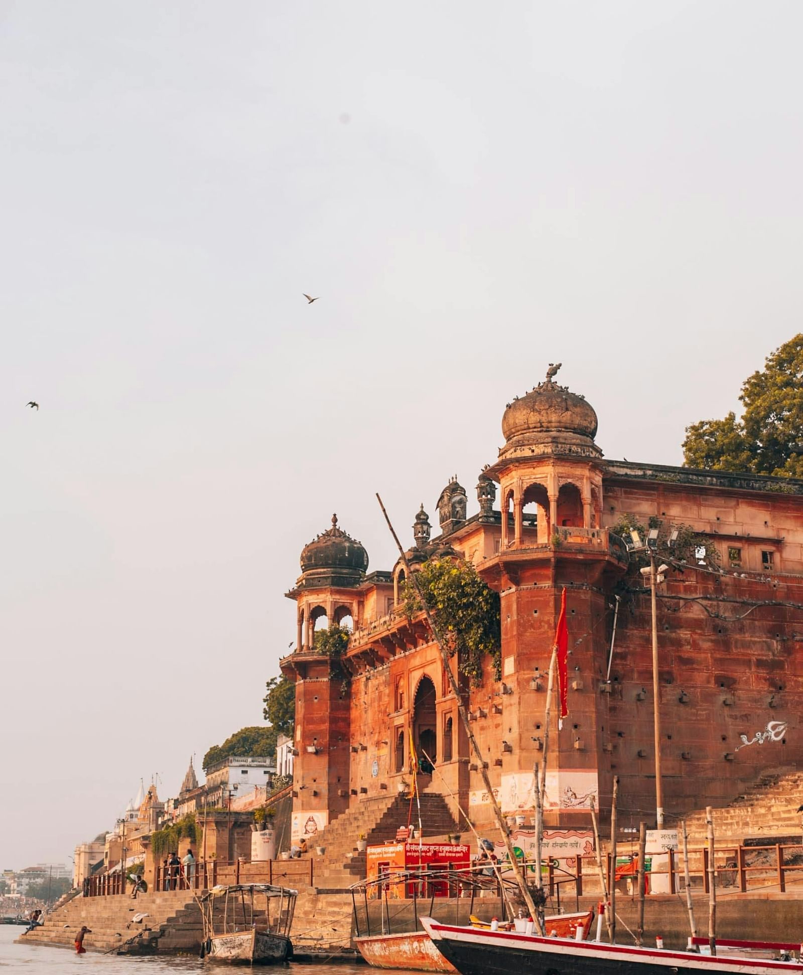 A serene riverside scene with traditional architecture and boats along the Ganges in Varanasi