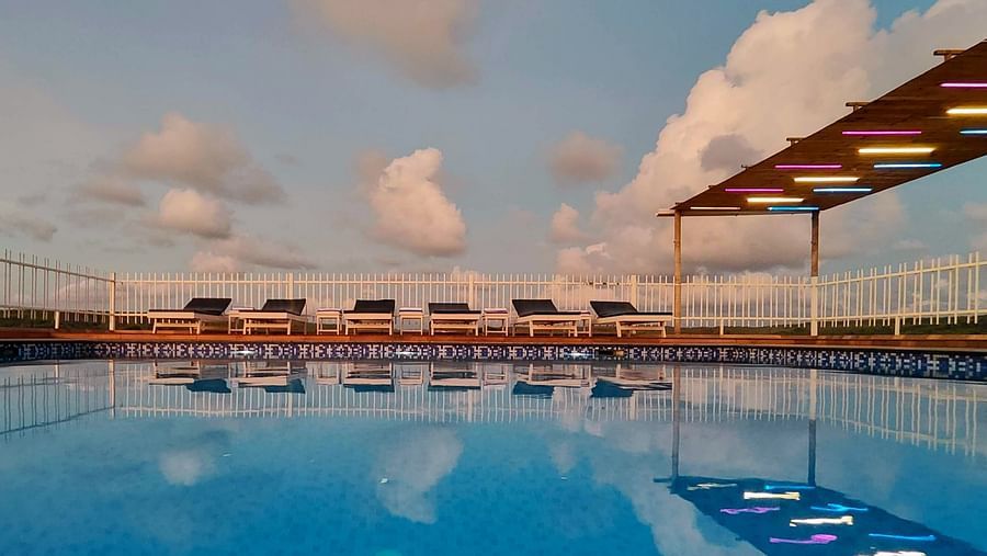 Swimming pool with seating chairs around it at Vagator Downtown, Goa