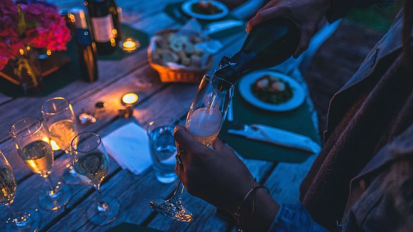 a group of people wining and dining on a desk with food & drinks places on the deck