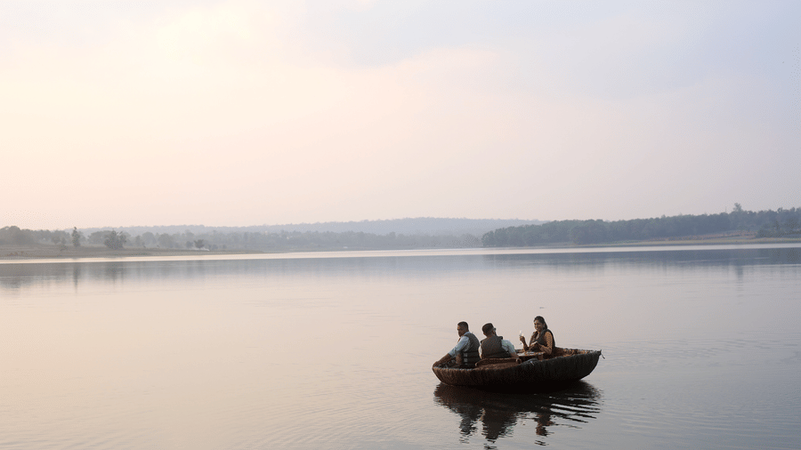 A small boat on the calm Kabini river at sunset near Evolve Back resort