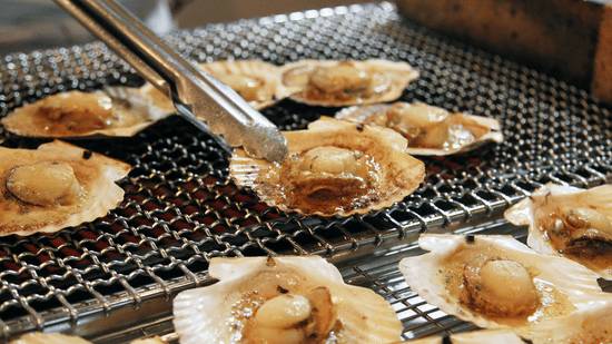 Scallops are being grilled over hot coals on a barbecue.