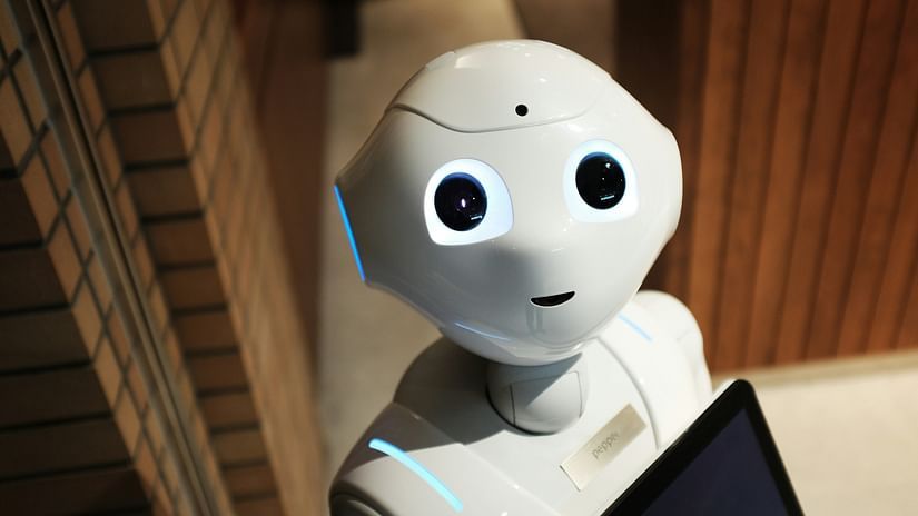 A robot looking at the camera holding a tablet computer to show automation.