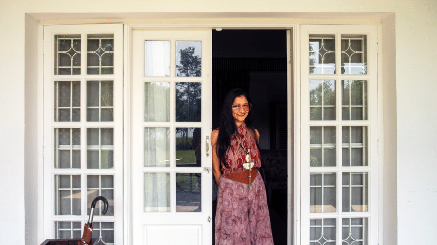 A guest stands at the entrance of the Waterfront Verandah at The Serai Kabini, viewed from the outdoor verandah area.