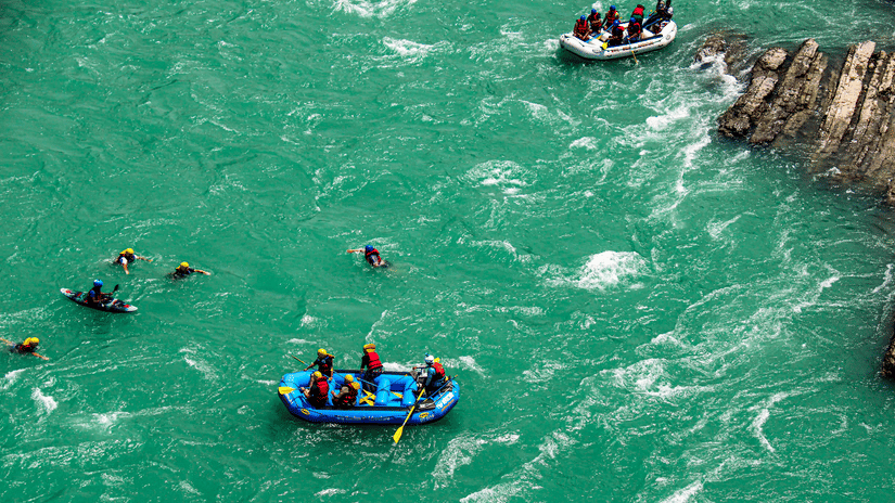 A group of people in different rafts rafting with a paddle.