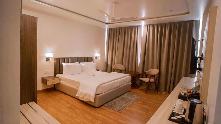 A corner view of the bedroom with comfy bed, chair, kettle etc at at Mastiff Select Medha Plaza, Deoghar