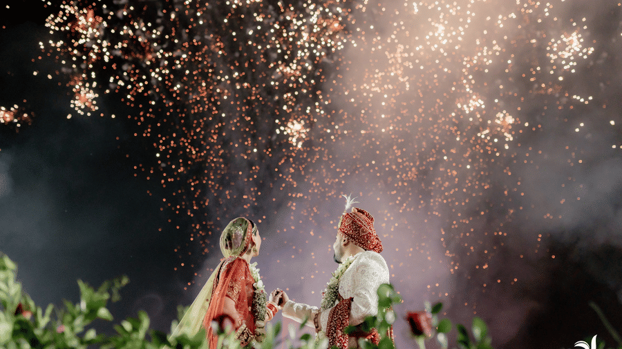 Bride and groom celebrating under fireworks during a night wedding event.