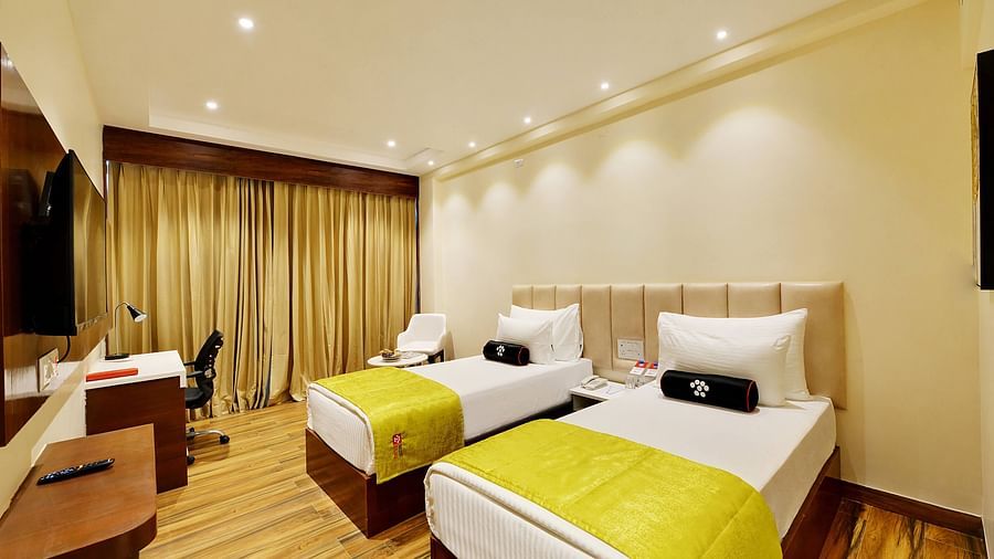 room with twin beds in white linens and yellow comforter.