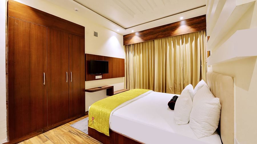 suite bedroom side view - ample lighting, champagne curtains and white linens make the room chic and classy.