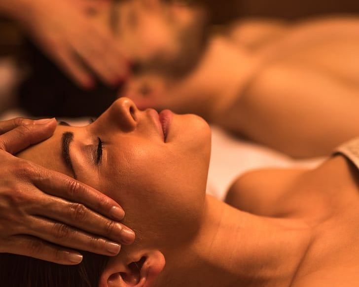Woman receiving a relaxing facial massage in a dimly lit spa environment.