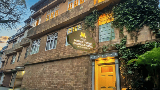 Mount Thistle Boutique Hotel in Darjeeling featuring a rustic stone exterior, ivy-covered walls, warm-lit windows, and a cosy boutique entrance.