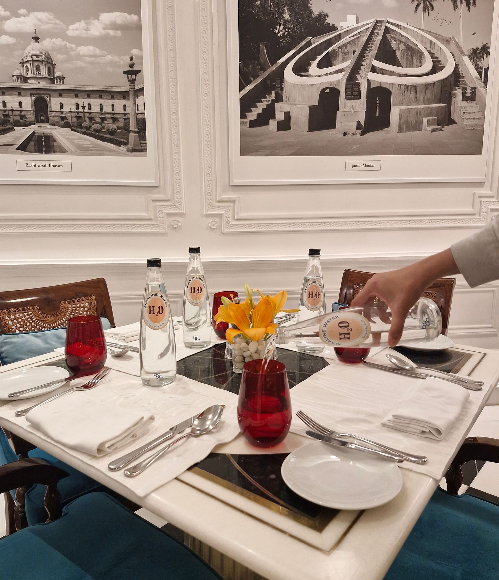 An image of a table setup with alkaline water being poured from a bottle into a glass - Claridges Collection