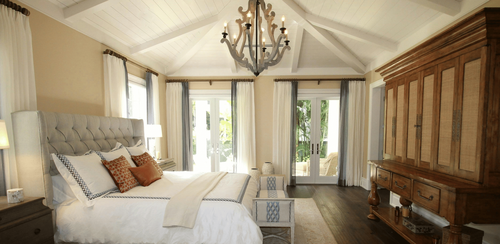 Side view image of the bed with a chandelier hanging over the double bed.