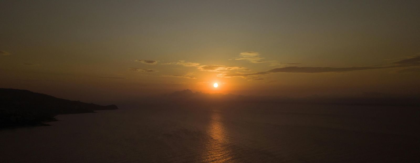A golden sunset over calm sea, casting a warm glow and peaceful reflections.