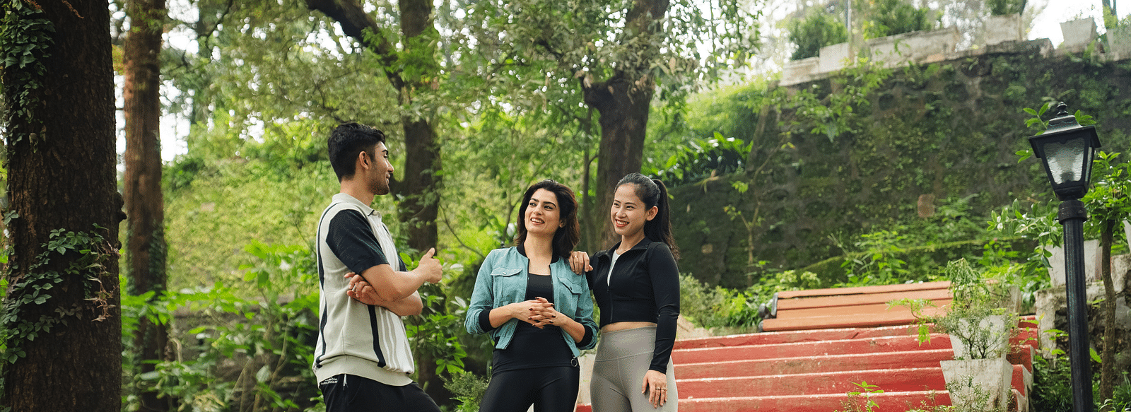 Three people chatting on red steps surrounded by greenery in nature