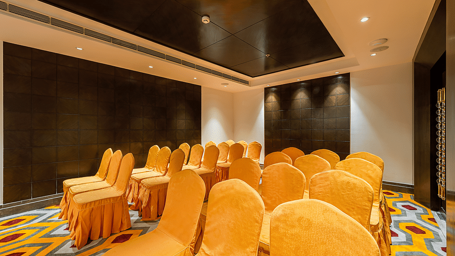 Conference room with yellow-orange chair covers, a dark tiled wall and a patterned carpet - TGI Grand Fortuna, Hosur