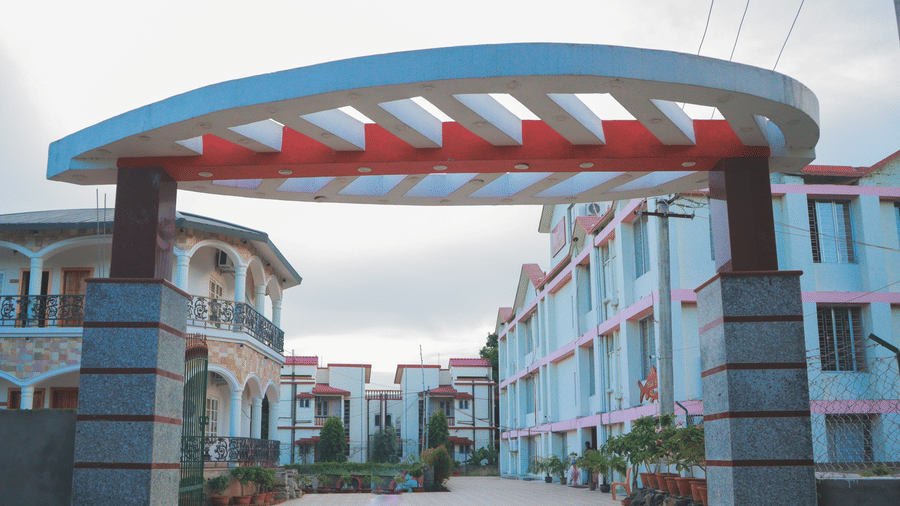The main entry gate to Dip Holidays in Birbhum, featuring a designed arch and driveway leading to paved walkways and multiple boutique buildings inside.