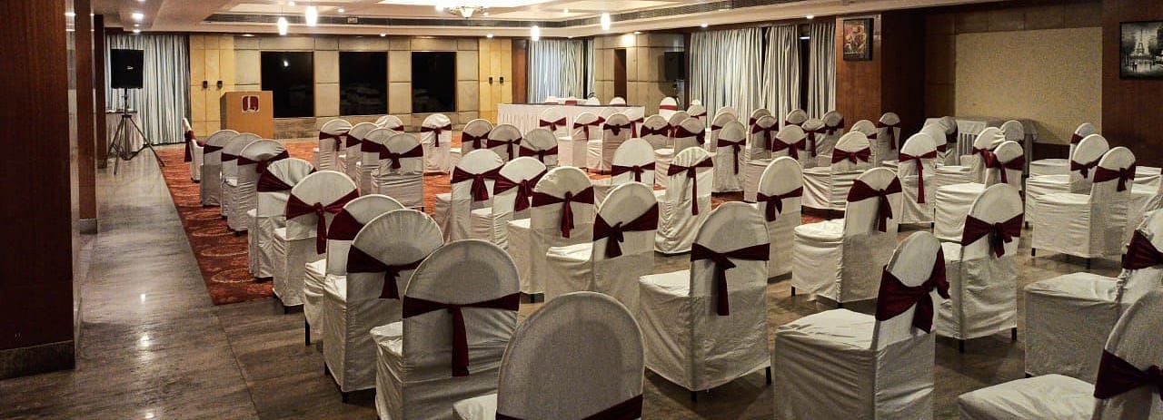 A well-lit banquet hall of Lords Plaza Ankleshwar with theatre style seating and elegant interiors creating a warm ambience