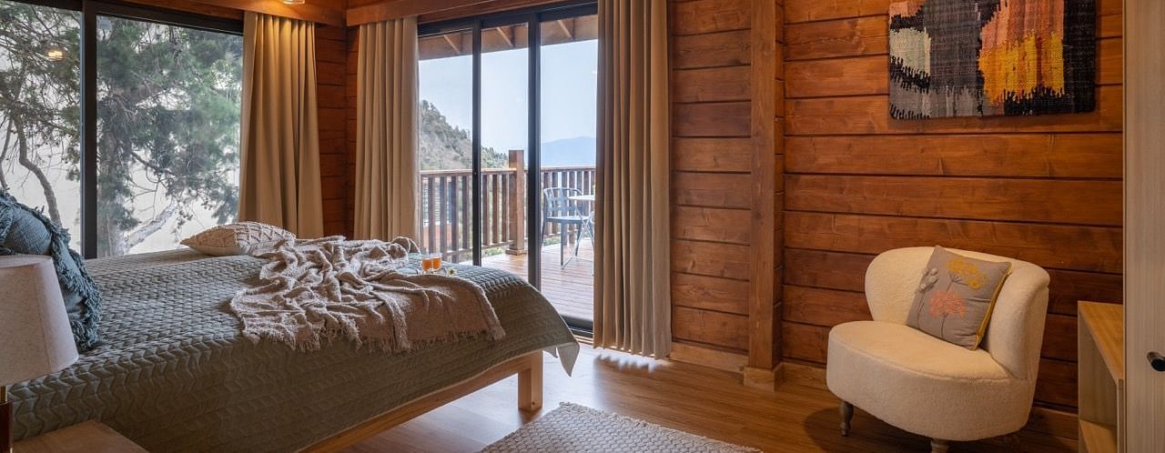 An image of a bedroom with bedside table, sofa, and an attached balcony - Avalon Cottages, Kanatal